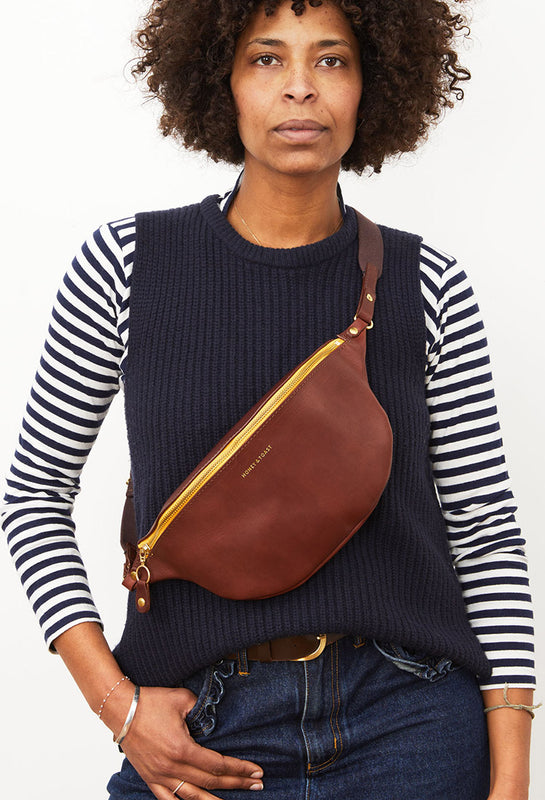 Woman wearing a leather sling bag on her front and back